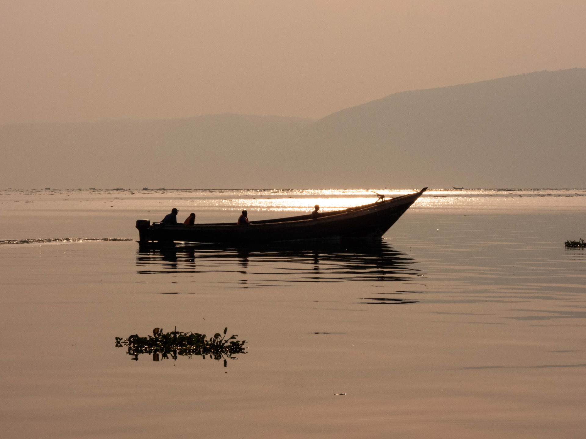 A boat silhouetted on calm water at sunset