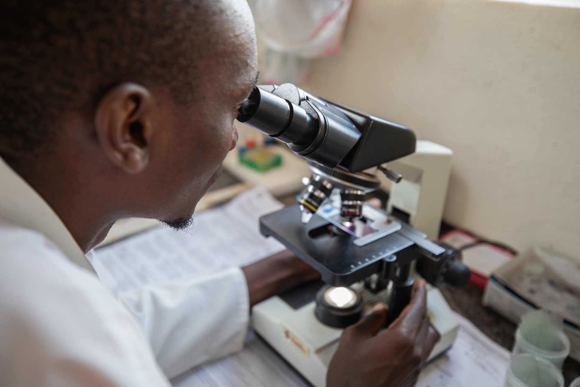 Ugandan health worker examining a sample under a microscope